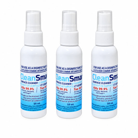 Front view of three CleanSmart Surface Cleaner & Disinfectant 59 mL travel-size spray bottles with blue bilingual labels and white spray caps.