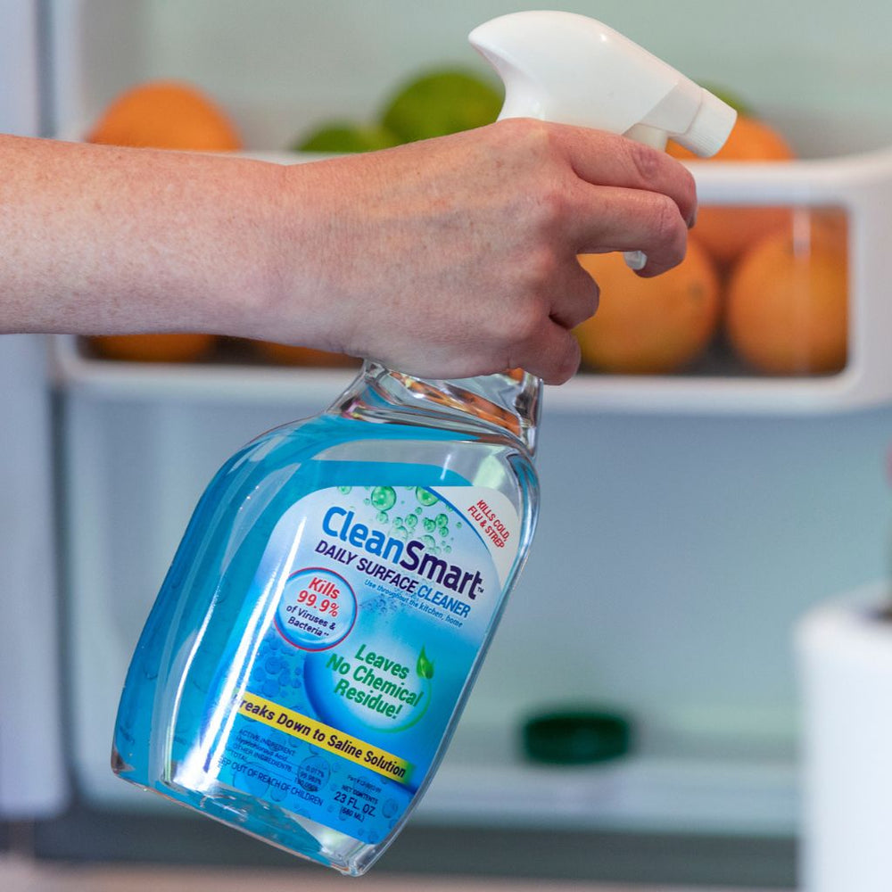 Hand holding a bottle of CleanSmart daily surface cleaner with a blurred background of oranges - CleanSmart Canada